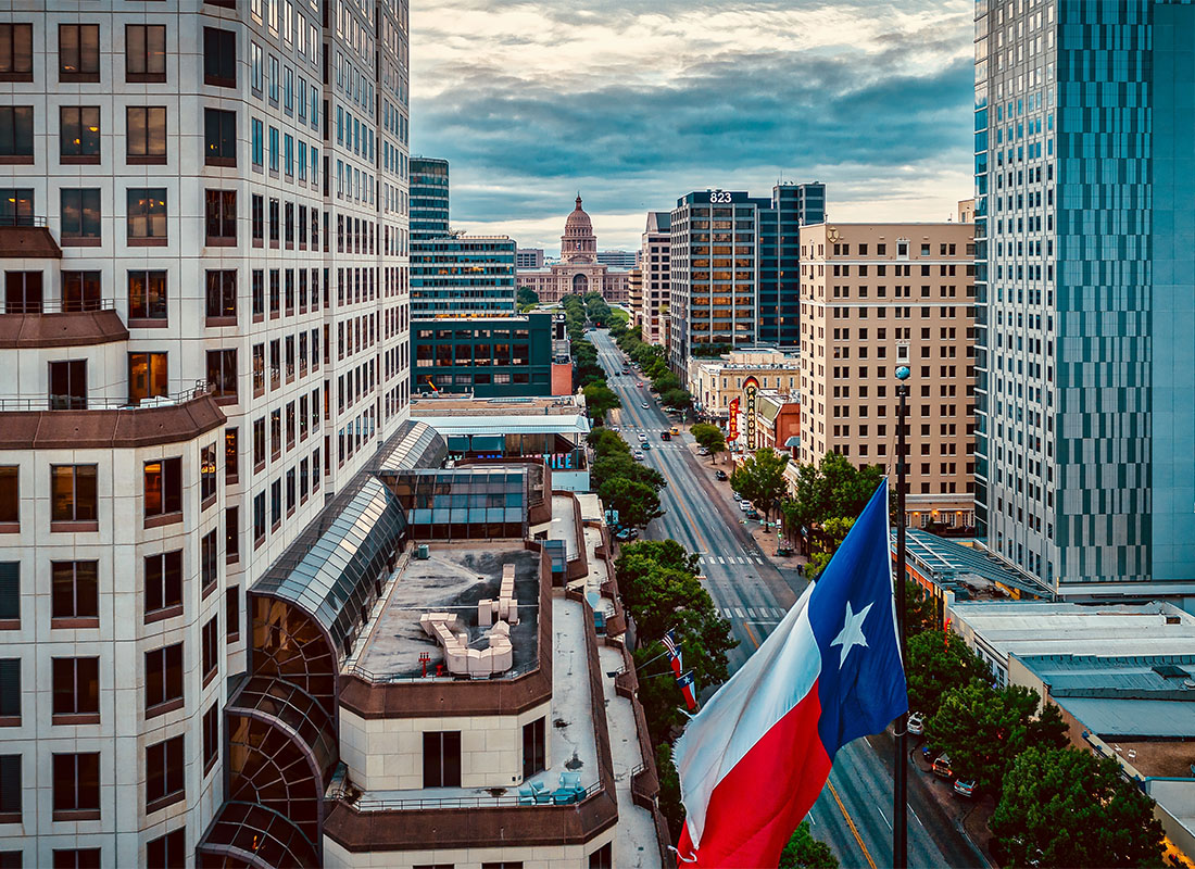 Service Center - Aerial View of Office and Commercial Buildings in Downtown Austin Texas Next to a Lone Star Flag on a Sunny Day