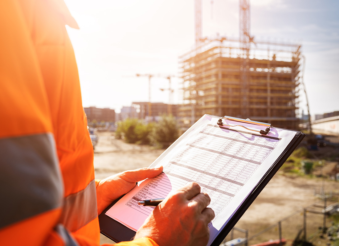 Safety and Loss Control Insurance - Closeup View of a Male OSHA Inspector Holding a Clipboard with a Checklist on a Construction Jobsite